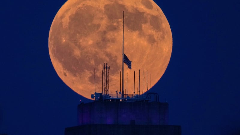 La Luna llena se alza por detrás del ayuntamiento en el centro de Kansas City, Misuri, antes...