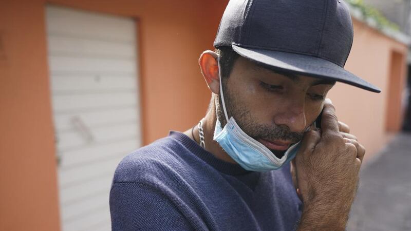 El venezolano José Cuicas escucha un mensaje de audio en su celular en el exterior de un...