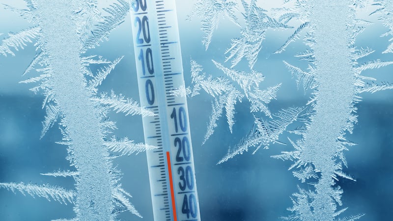 Frosty winter window with ice patterns and a thermometer showing a minus temperature.