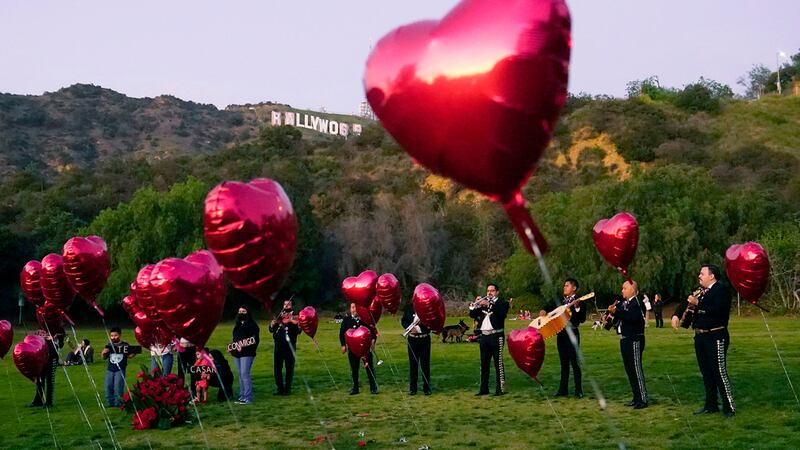 ARCHIVO - Una banda mariachi mexicana rodeada por globos en forma de corazón aguarda el arribo...