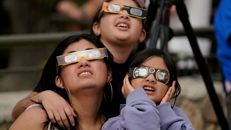 ARCHIVO - Un grupo de espectadores utiliza unas gafas especiales para ver cómo la Luna se...