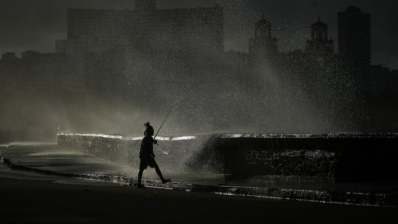 Una persona pesca en el muelle mientras las olas rompen durante un apagón en La Habana, el...