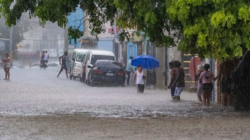Gente camina por una calle inundada por las lluvias de la tormenta tropical Franklin en Santo...