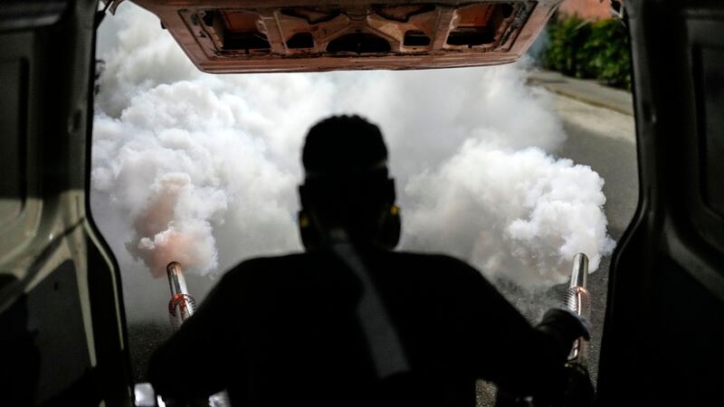 Un trabajador fumiga un vecindario contra el mosquito que propaga el dengue, en Caracas,...