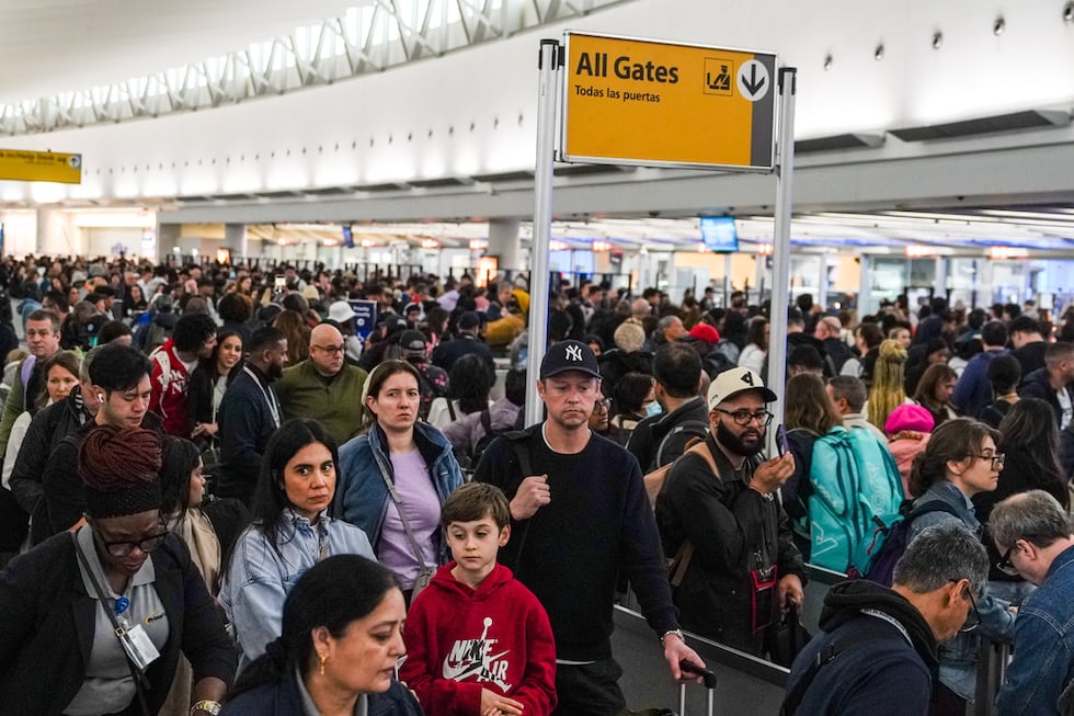 Personas hacen largas filas en el punto de revisión de seguridad en el Aeropuerto...