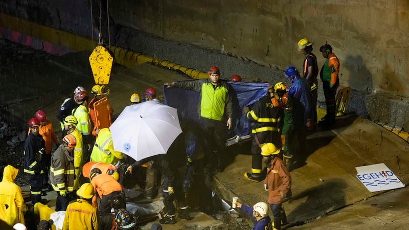 Equipos de rescate trabajan en el lugar donde se derrumbó un muro en la entrada de un túnel en...