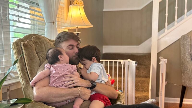 El veterano de marines Adrian Clouatre abraza a su hija de 3 meses, Lyn y a su hijo de casi...