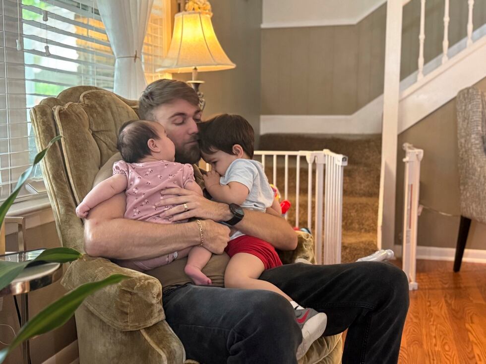 El veterano de marines Adrian Clouatre abraza a su hija de 3 meses, Lyn y a su hijo de casi...