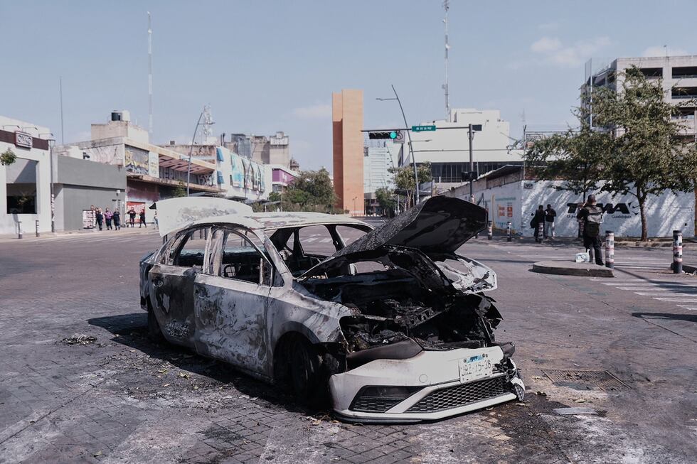 Un vehículo yace carbonizado tras ser incendiado en una avenida de Guadalajara, en el estado...