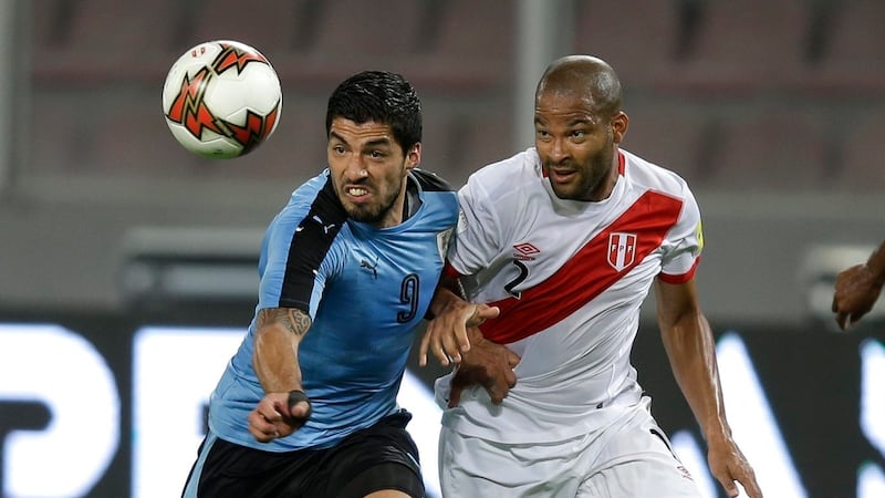 El uruguayo Luis Suárez (izquierda) lucha por el balón con el peruano Alberto Rodríguez...