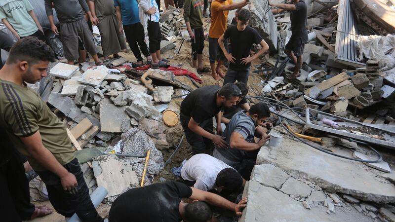 Palestinos buscan sobrevivientes entre los escombros tras un ataque israelí en Rafah, en la...