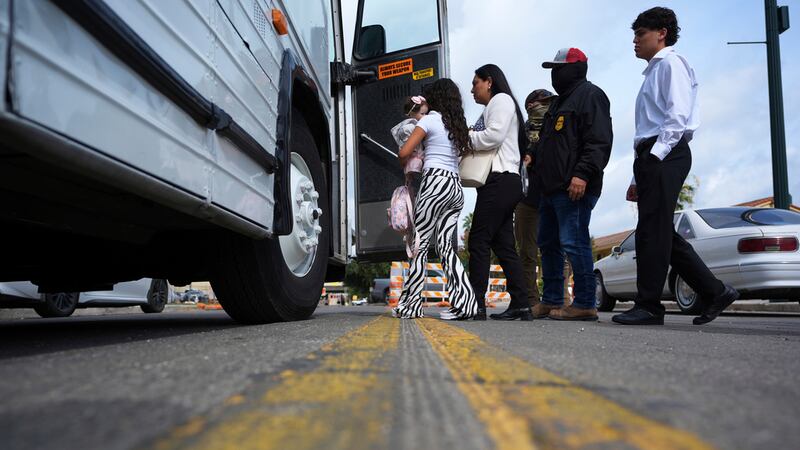 Una familia procedente de Colombia es detenida y escoltada a un autobús por agentes federales...