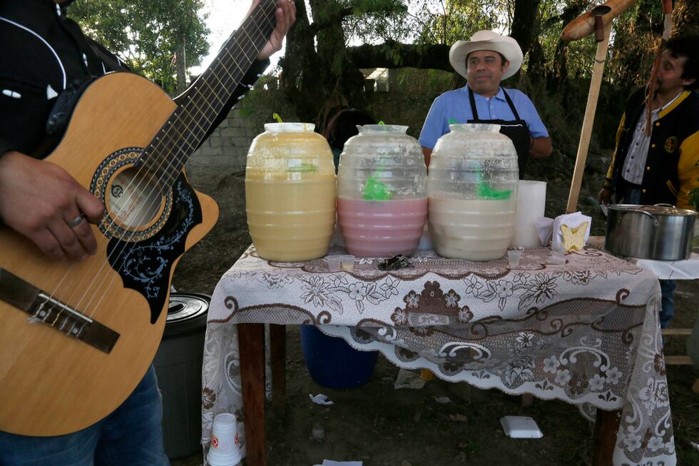 ARCHIVO - Un músico afina su guitarra mientras un vendedor de pulque espera clientes en...