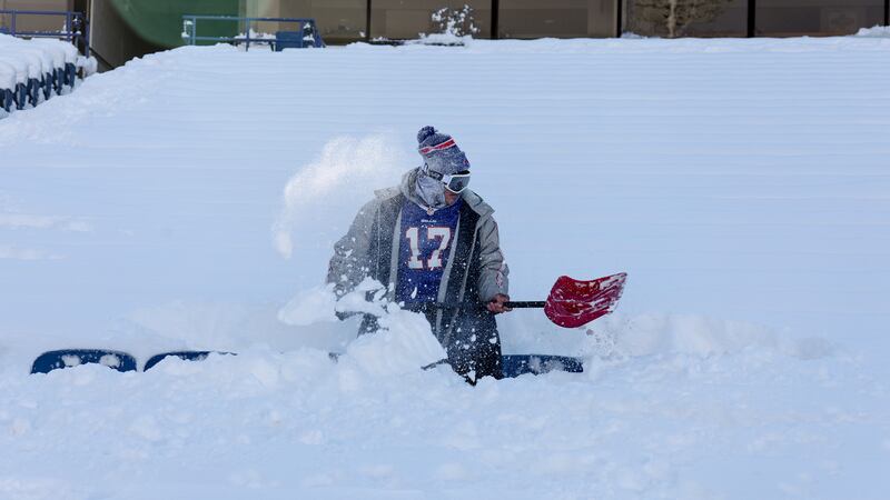 Un fanático de los Buffalo Bills quita la nieve de su fila de asientos antes de un partido de...