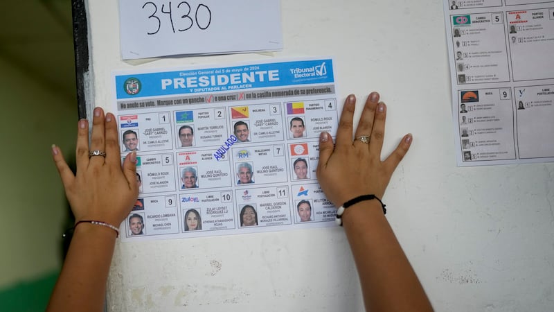 Un trabajador electoral coloca en una pizarra una papeleta de muestra en un centro de votación...