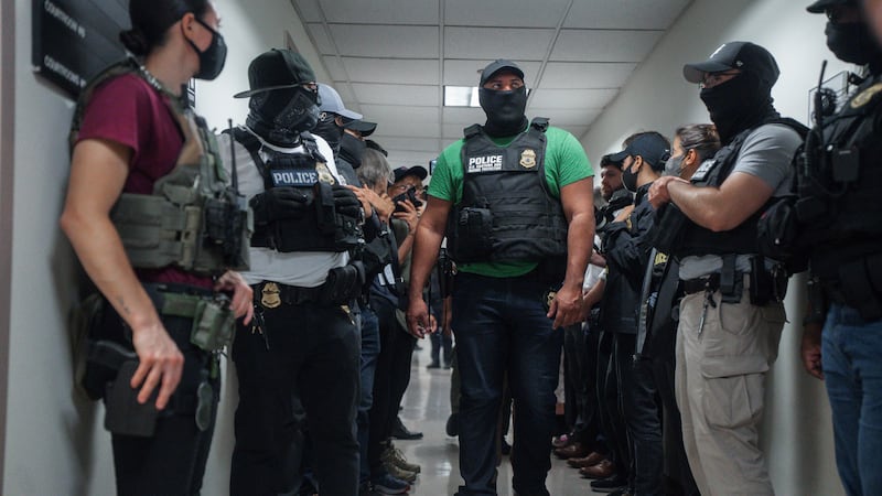 FILE - Masked federal agents wait outside an immigration courtroom, July 8, 2025, in New York.