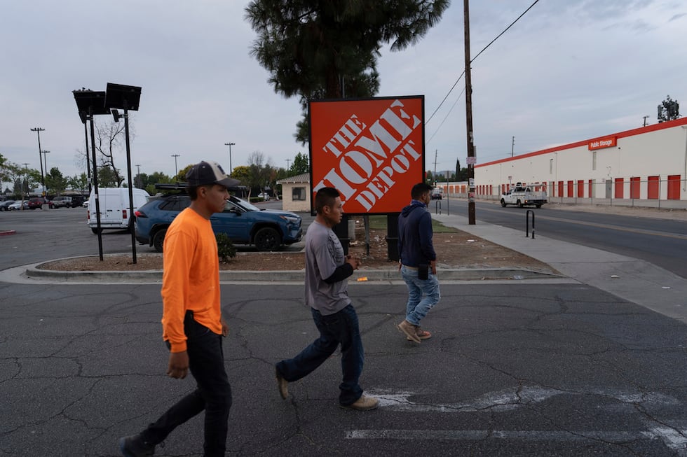 Trabajadores se dirigen a un vendedor de alimentos frente a un letrero de Home Depot en el...