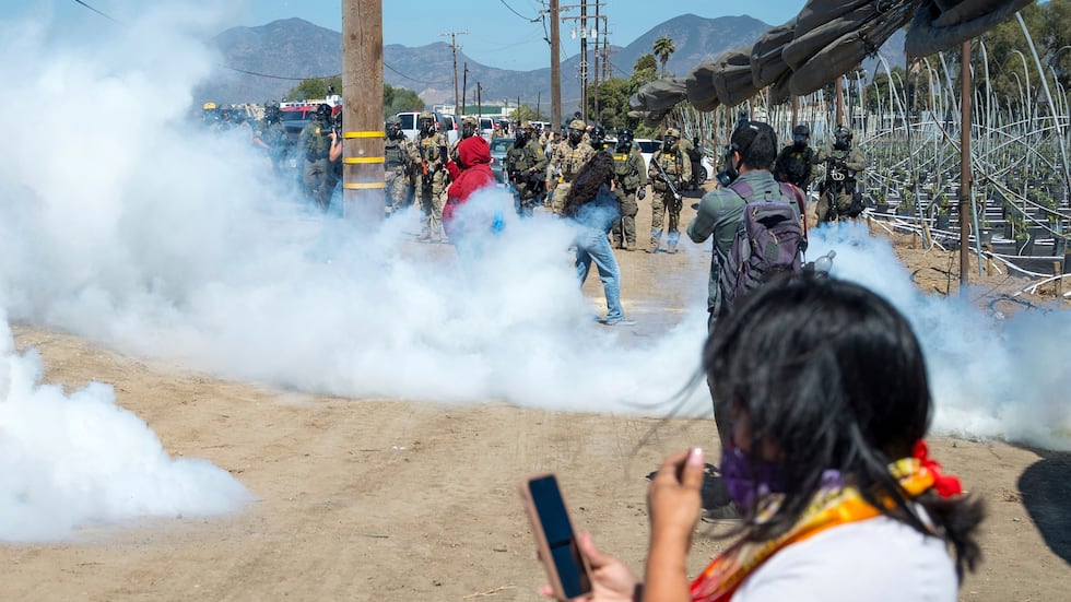 Federal immigration agents toss tear gas at protesters during a raid in the agriculture area...
