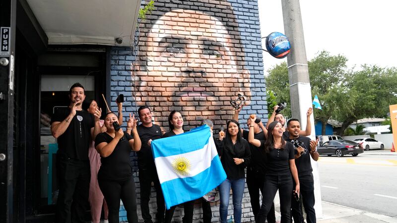 Personal del restaurante Fiorito porta una bandera de Argentina frente a un mural de Lionel...
