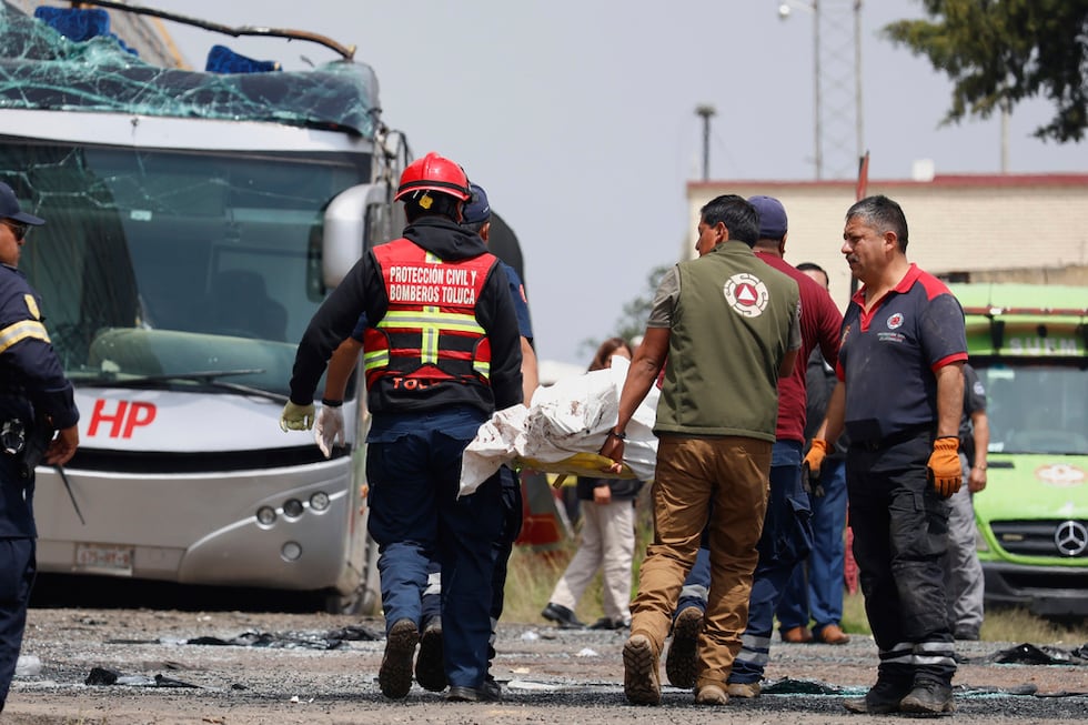 Los equipos de rescate retiran un cuerpo de la escena de un accidente mortal entre un tren y...