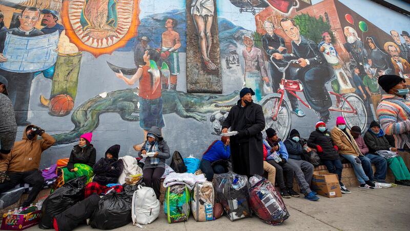 Migrantes comen y esperan ayuda, acampados en una calle del centro de El Paso, Texas, 18 de...