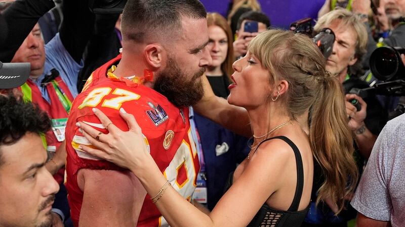 El tight end de los Chiefs de Kansas City Travis Kelce (87) habla con Taylor Swift después del...