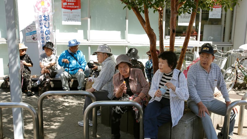 Varias personas mayores descansan a la sombra de un árbol en Tokio, el 14 de septiembre de...