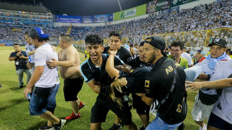 Un grupo de hinchas carga a un aficionado herido hacia la cancha del estadio de Cuscatlán en...