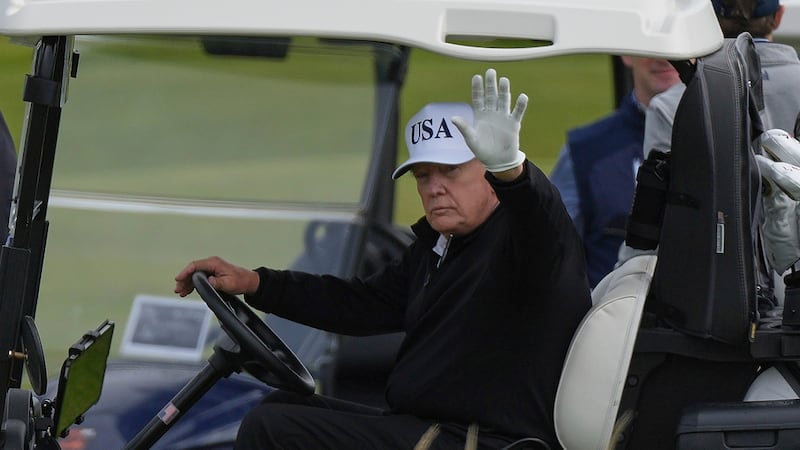 El presidente estadounidense Donald Trump saluda a los periodistas mientras recorre el campo...