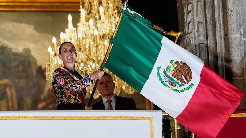La presidenta de México, Claudia Sheinbaum, ondea una bandera mexicana durante el inicio de...