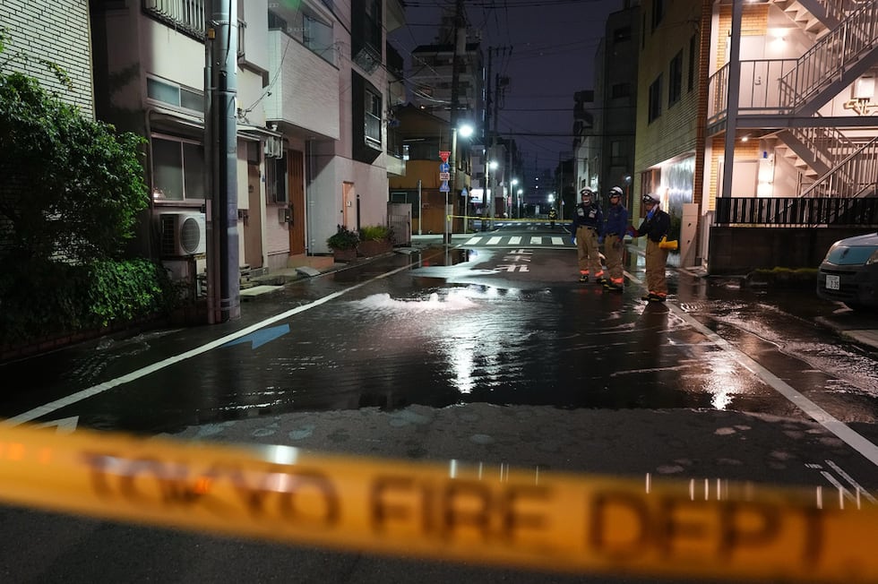 Rescatistas del Departamento de Bomberos de Tokio junto a un camino parcialmente inundado, la...