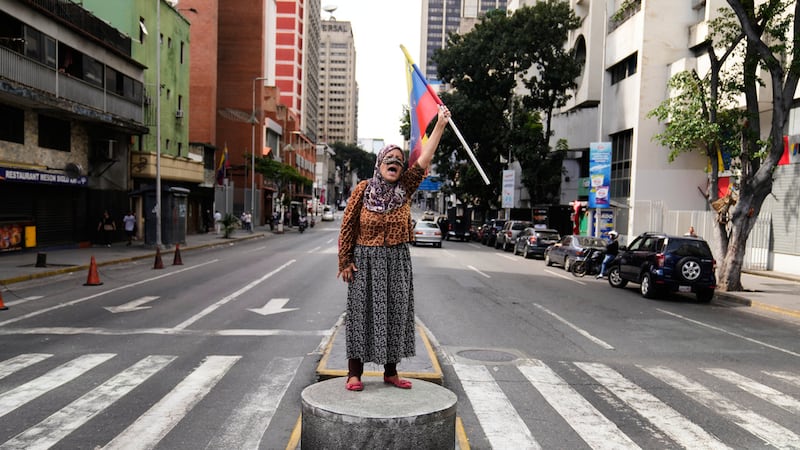 Un simpatizante del presidente venezolano Nicolás Maduro se encuentra en una mediana ondeando...