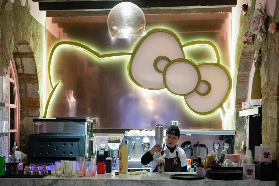 Una empleada de un café con temática de Hello Kitty prepara una bebida para fans del personaje...