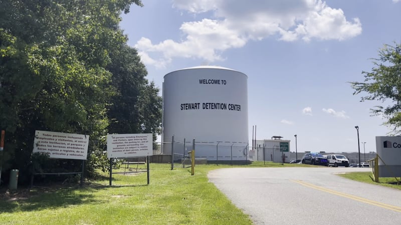 A water tower reading "Welcome to Stewart Detention Center" stands behind a security fence at...