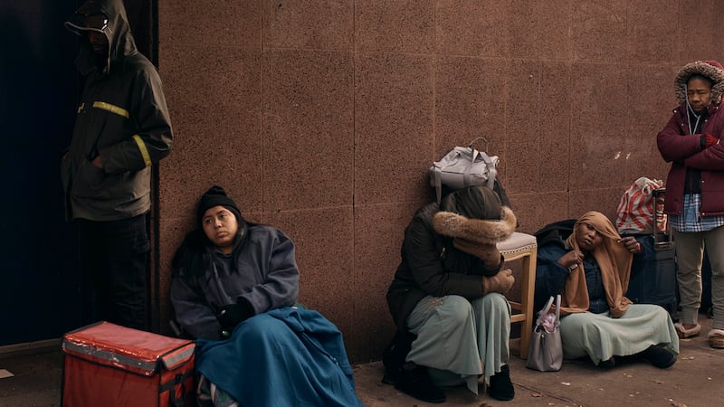 Migrantes hacen fila a la intemperie en el exterior de un centro de ayuda habilitado en la...