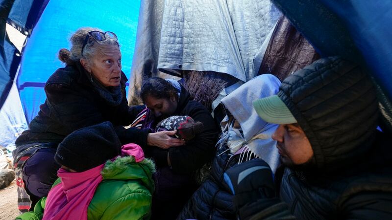 ARCHIVO - La doctora voluntaria Karen Parker, a la izquierda, toca la cabeza de un niño con...