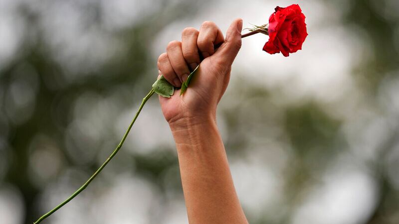 Una manifestante levanta el puño al aire con una rosa roja durante una protesta en Manila,...