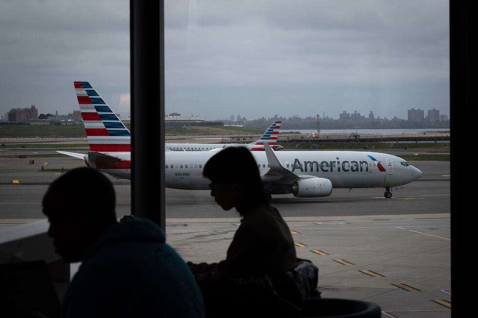 Gente esperando a vuelos mientras un avión de American Airlines circula por la pista en el...