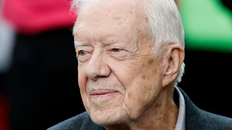 ARCHIVO - El expresidente Jimmy Carter sonríe en la banca de los Falcons de Atlanta antes del...