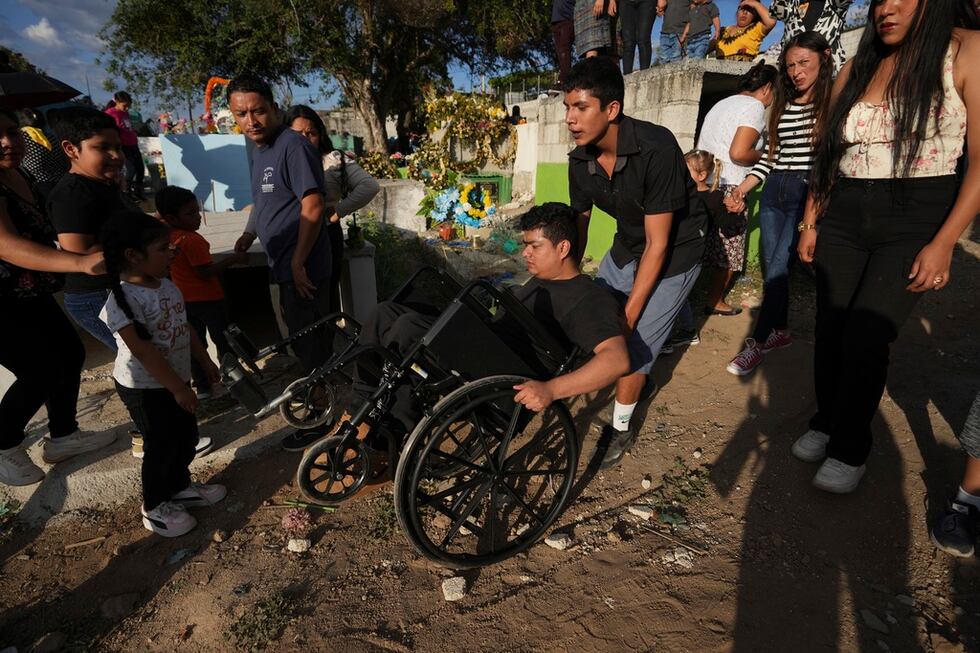 Christian Pérez llega en silla de ruedas, ayudado por un amigo, al cementerio para el entierro...