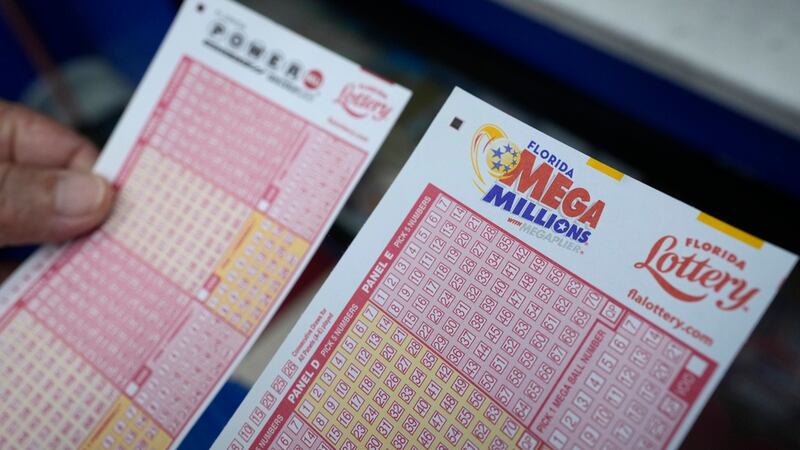 Un jugador de lotería sostiene formas para escoger números de las loterías Powerball y Mega...