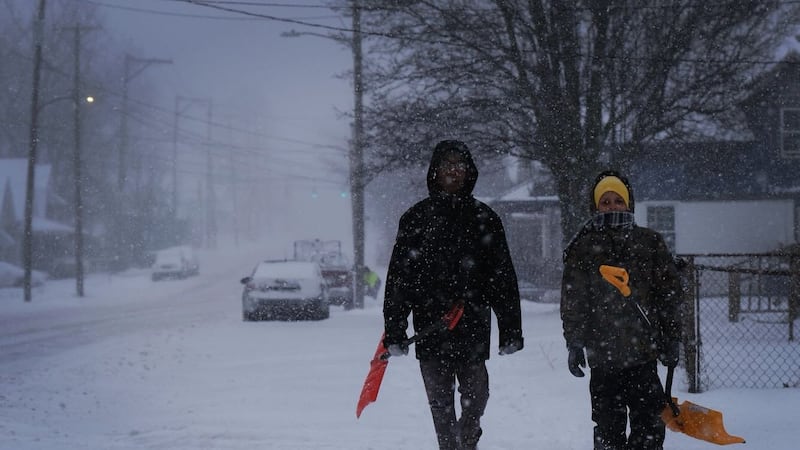Two kids walk down Western Avenue in Toledo as snow falls on Sunday, Jan. 25, 2026.