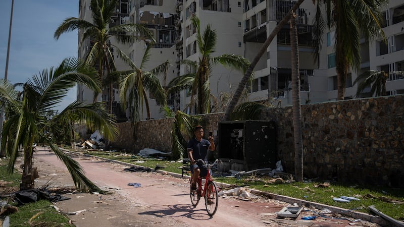 Un hombre pasa en bicicleta por una zona dañada por el huracán Otis en Acapulco, México, el...