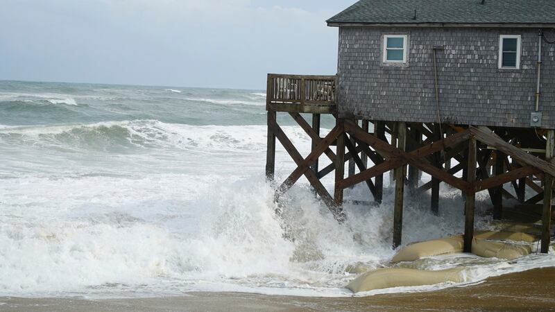 Las olas del huracán Erin rompen contra los pilotes --protegidos con sacos de arena-- de una...