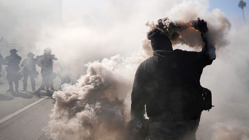 Un manifestante arroja una lata de gas lacrimógeno cerca del Centro de Detención...