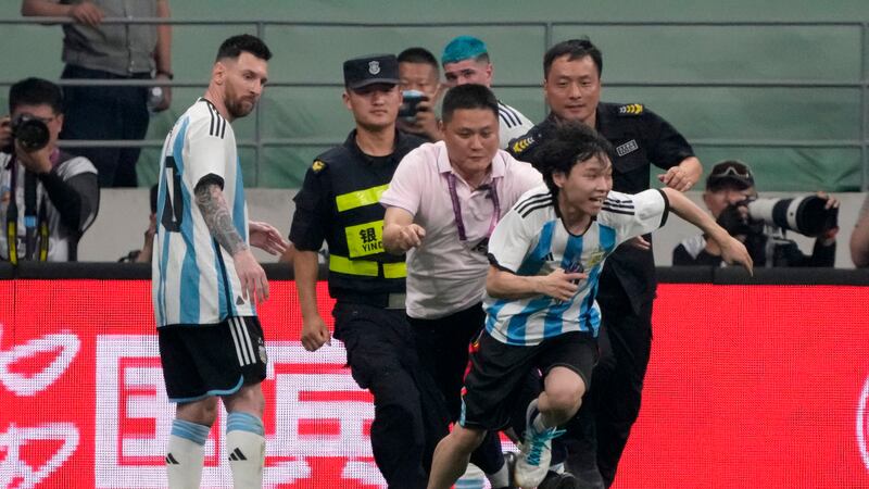 El delantero argentino Lionel Messi (izquierda) observa cuando la seguridad persigue a un...