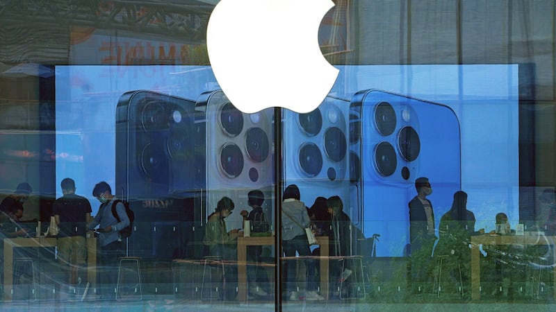 FILE - People try out iPhone products at an Apple Store in Beijing on Sept. 28, 2021. Apple's...