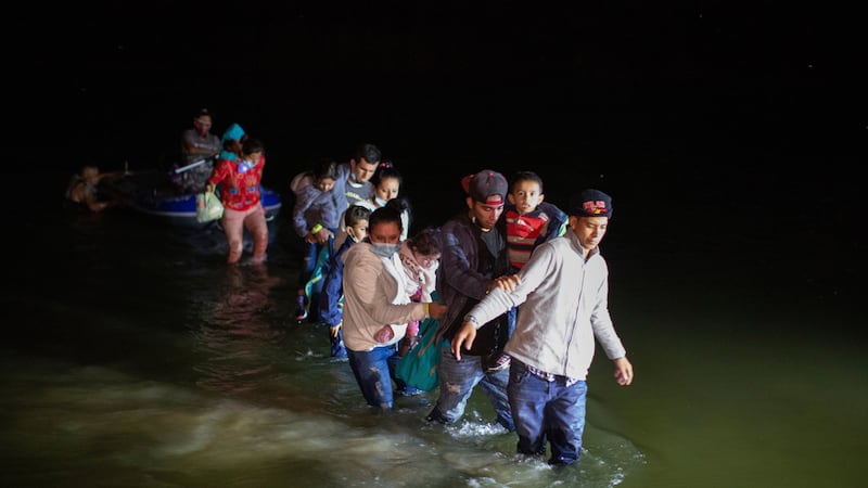 ARCHIVO - Familias migrantes cruzan aguas poco profundas el 24 de marzo de 2021, en dirección...