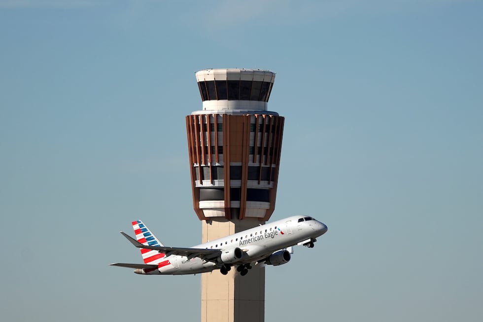 Un avión American Eagle de American Airlines pasa por la torre de control de tráfico aéreo en...