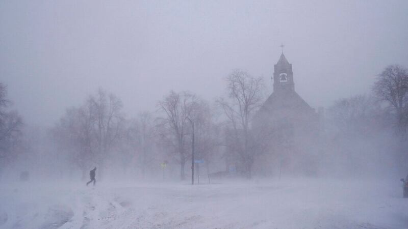Un peatón con equipo para la nieve avanza por el Colonial Circle, con la silueta de la iglesia...